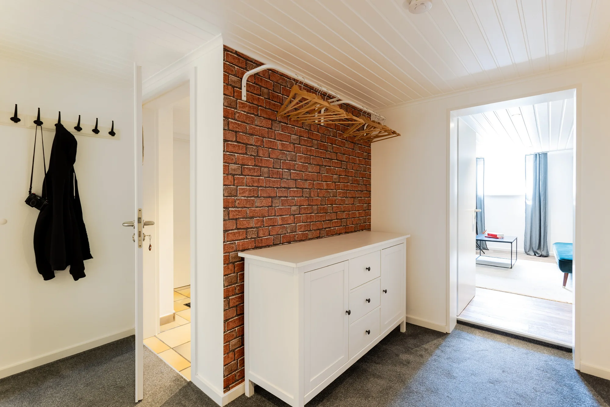 Eingangsbereich mit Backsteinwand und Kommode